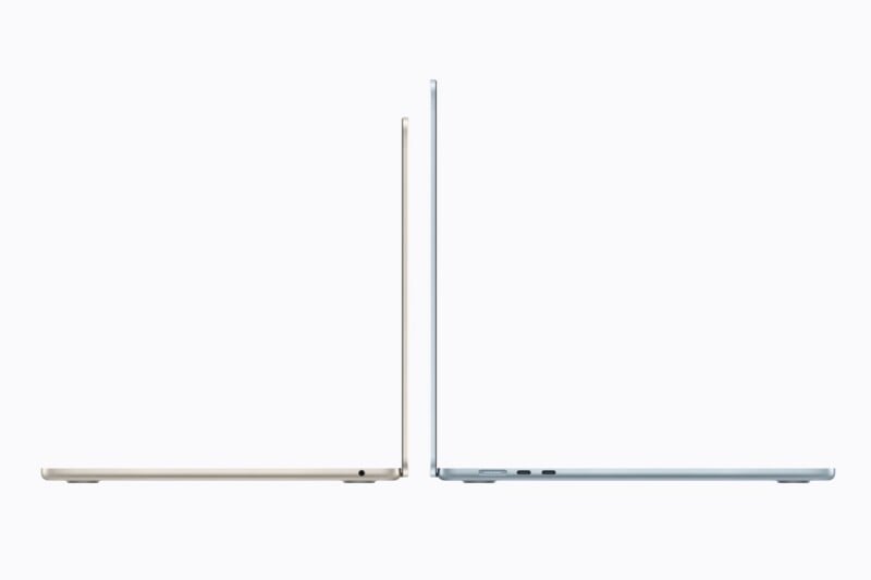Side view of two thin laptops, one in a light beige color and the other in light blue, both partially open and positioned facing each other on a plain, light background.