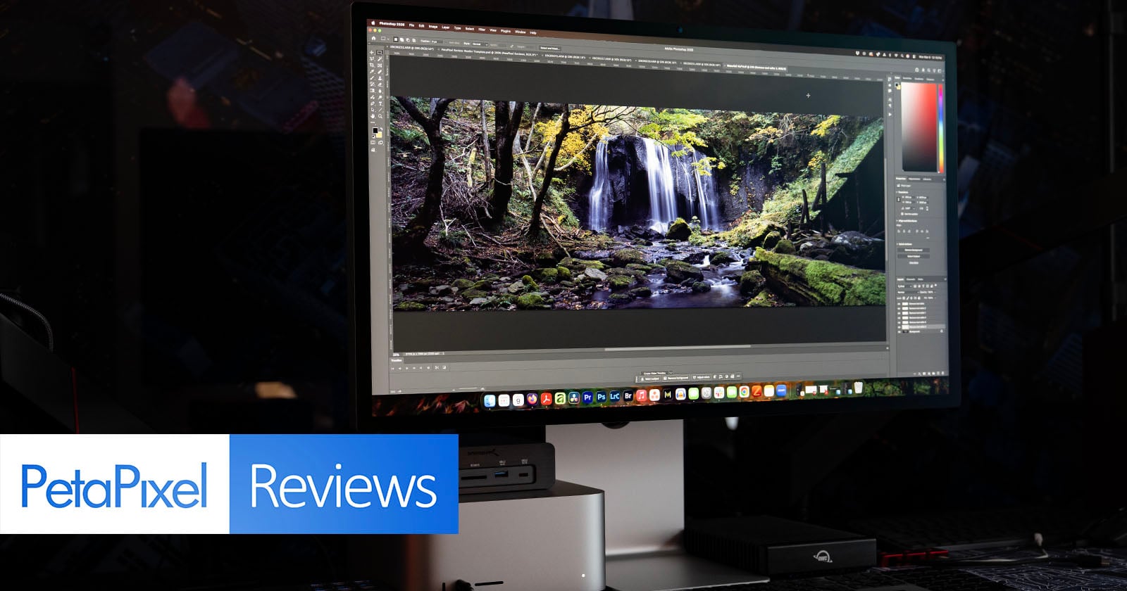 A desktop monitor displays a photo editing software with an image of a forest waterfall. The scene is dark, and the PetaPixel Reviews logo appears in the lower left corner.