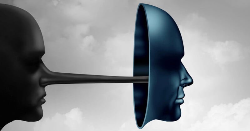 A dark face with a long, Pinocchio-like nose pushes through a mask shaped like a human face, set against a cloudy sky background, symbolizing deception or hiding one's true identity.