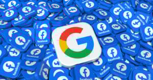 A large 3D Google logo cube is surrounded by numerous blue cubes displaying the Facebook logo and text on their surfaces.