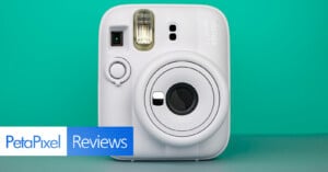 A white Fujifilm Instax Mini 13 instant camera is centered against a teal background. The bottom left features a "PetaPixel Reviews" banner.
