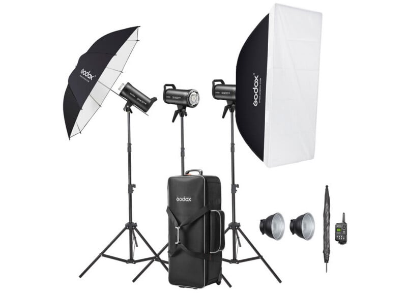 En el stand hay dos luces estroboscópicas de estudio Godox con softbox y paraguas, dos reflectores, un control remoto y un gran estuche negro para transportar el kit de iluminación fotográfica.