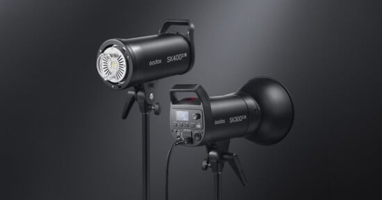 Two black Godox SK400II studio lights on stands; one shows the front with the LED light, the other shows the back with a digital display and control buttons, both against a dark gradient background.