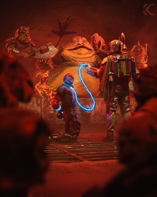 A toy scene depicts Jabba the Hutt surrounded by his entourage, as Boba Fett holds a glowing blue whip-like weapon toward a kneeling figure, with onlookers in the dimly lit background.