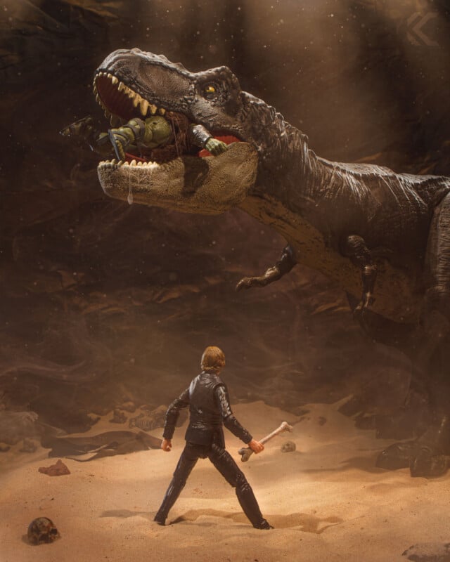 A toy figure of a man with a sword faces a large, roaring dinosaur in a dramatic, smoky desert scene; another figure is trapped in the dinosaur’s mouth.
