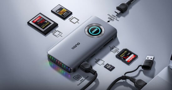 A sleek gray llano USB hub with multiple ports, connected to cables and SD cards. Labels indicate HDMI, USB-C, SD/TF card slots, and ethernet port. The device features a circular blue LED display on top.