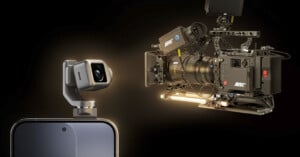 A close-up of a smartphone with a small camera module attached, facing a large professional ARRI cinema camera against a dark background. Both cameras are highlighted, emphasizing a contrast in size and technology.
