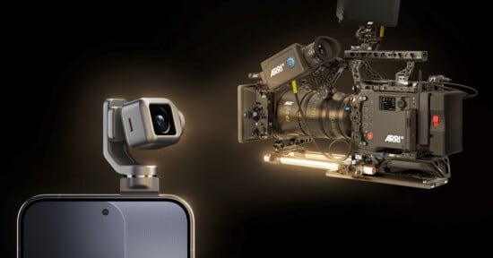 A close-up of a smartphone with a small camera module attached, facing a large professional ARRI cinema camera against a dark background. Both cameras are highlighted, emphasizing a contrast in size and technology.