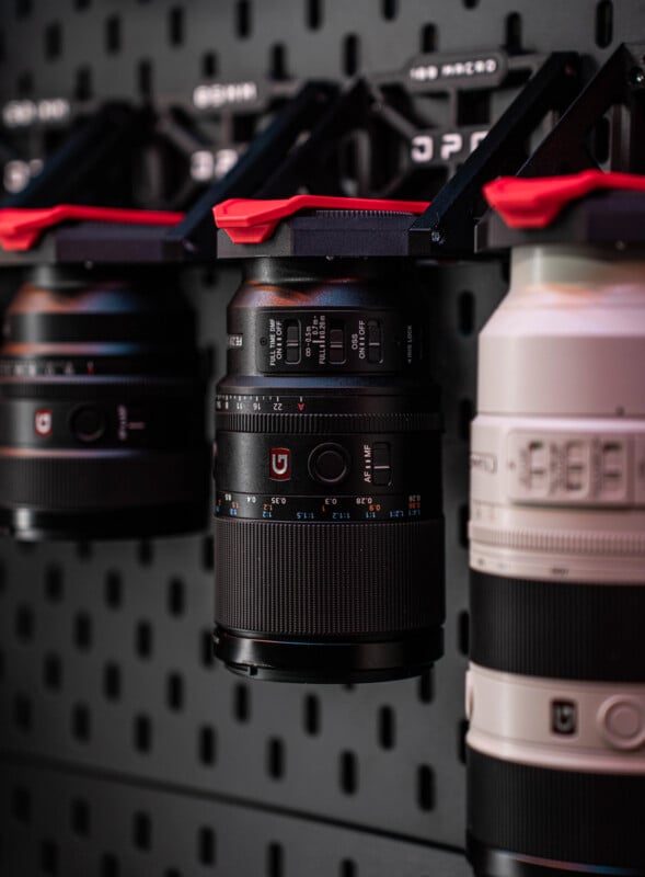 Tres lentes de cámara están montadas verticalmente sobre un tablero negro, con la lente del medio enfocada nítidamente y las otras dos ligeramente borrosas en el fondo.