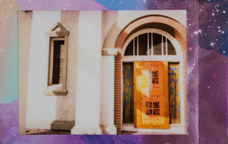 Una fotografía Polaroid de la entrada de un edificio con ventanas arqueadas y un tablero naranja con graffiti cubriendo la puerta. La foto tiene como fondo un fondo colorido, estrellado y con temática espacial.