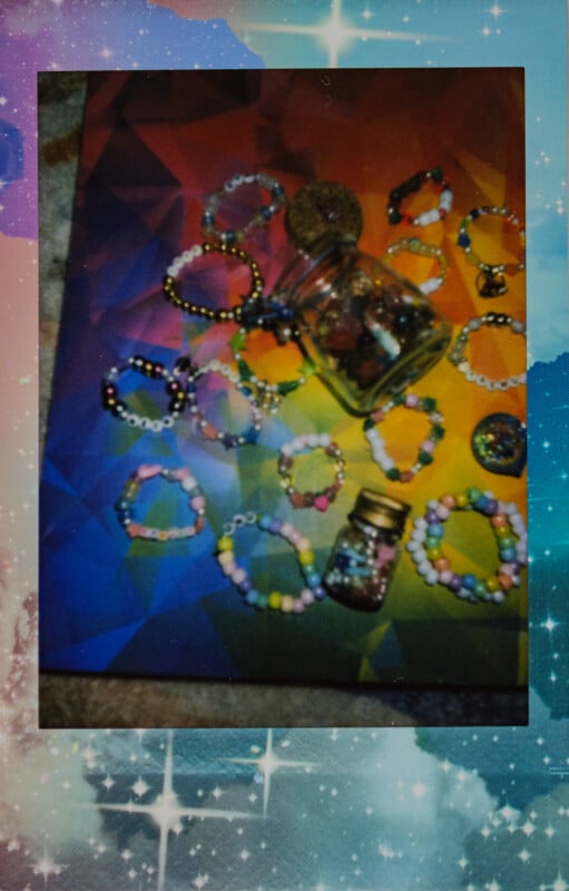 Una colorida pulsera de cuentas hecha a mano y dos pequeños frascos con cuentas dispuestas sobre un fondo geométrico de arcoíris con un borde de estrellas brillantes.