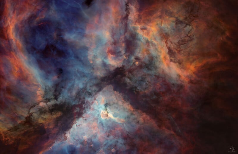 Coloridas nubes arremolinadas de gas interestelar y polvo en el espacio, con azules, naranjas y rojos mezclándose para crear una estructura nebular etérea y abstracta.