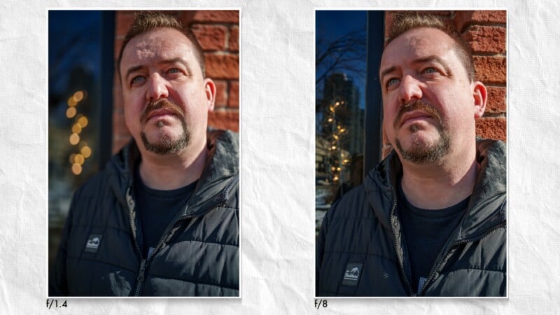 Side-by-side portraits of a man with short hair and a goatee, wearing a dark jacket, standing outside near a brick wall. The left photo (f/1.4) has a blurrier background; the right photo (f/8) is more in focus.