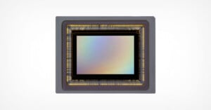 A rectangular camera image sensor with a metallic frame and rainbow-reflective surface, set against a plain white background.