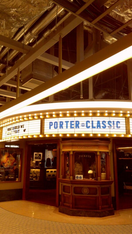 A vintage-style theater entrance with a lit marquee reading "PORTER CLASSIC" and "WHAT SHOULD WE TODAY." The ticket booth is below the sign, and the ceiling above shows exposed pipes and ducts.