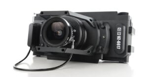 A black, boxy medium format camera with a prominent lens and a cable attached, labeled "VZ-6611" on the side, positioned on a white surface.
