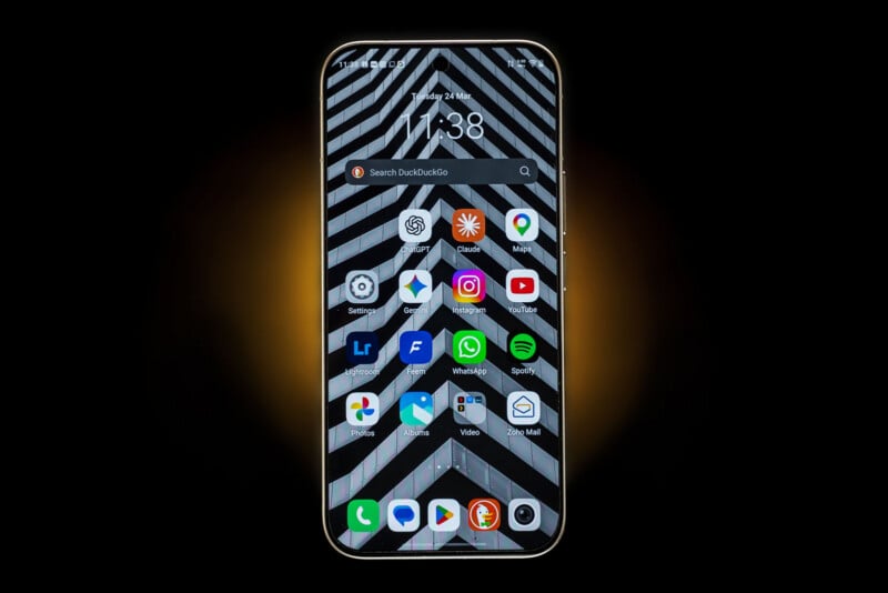 A smartphone with a geometric black-and-white wallpaper displays various app icons, including Instagram, WhatsApp, YouTube, Spotify, Gmail, and camera, on its home screen against a black background with a glowing orange halo.