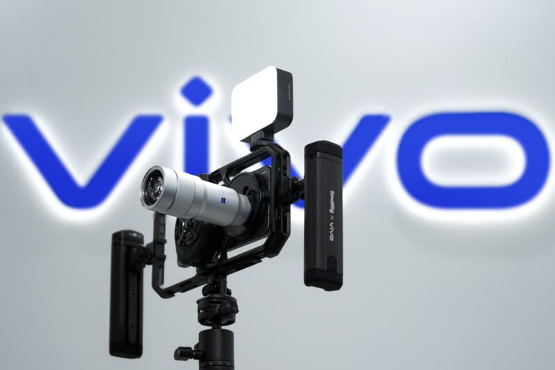 A professional camera rig with a Zeiss lens and accessories is mounted on a tripod. The background features the blurred blue and white "vivo" logo.