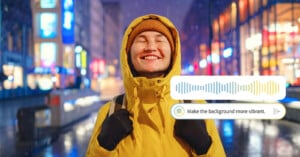 A smiling person in a yellow jacket and beanie stands on a brightly lit street at night. A digital overlay shows an audio waveform and the text: "Make the background more vibrant.