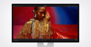 A computer monitor displays a vivid image of a woman wearing gold fringe and sparkling accessories against a red and blue glittery background, showcased in photo editing software.