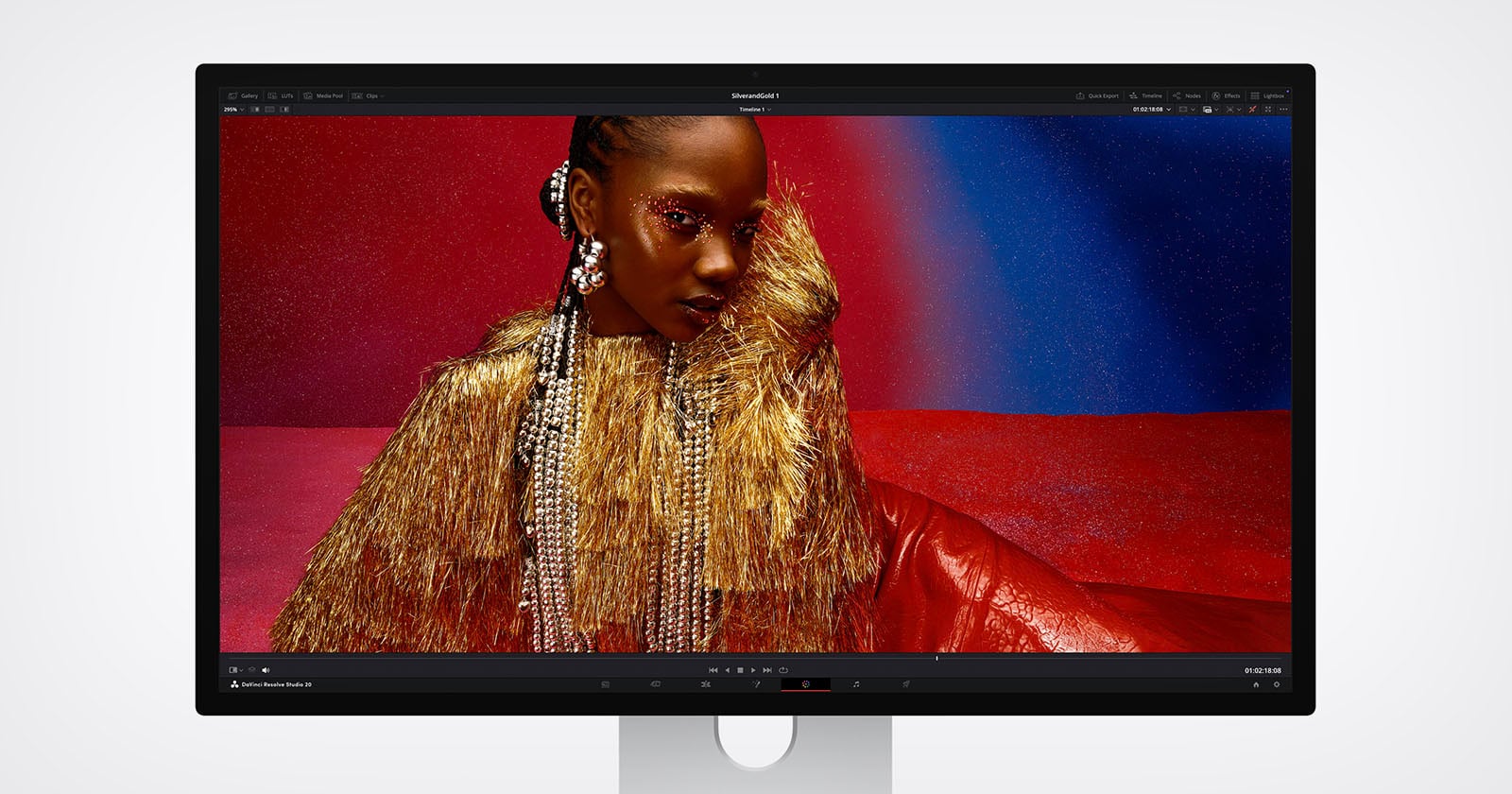 A computer monitor displays a vivid image of a woman wearing gold fringe and sparkling accessories against a red and blue glittery background, showcased in photo editing software.