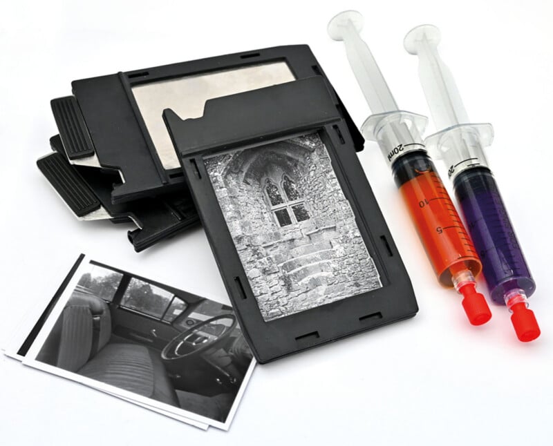 A stack of old photo slides, two syringes filled with red and purple liquid, and black-and-white photographs, including an image of stone steps and another of a car interior, are arranged on a white background.