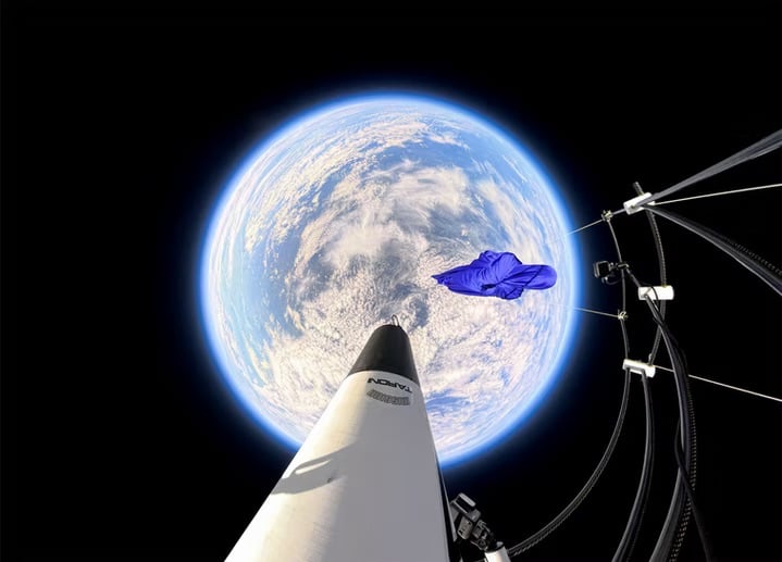 A view from a rocket in space shows the Earth below with a blue shirt floating nearby, surrounded by blackness and space equipment visible to the right.