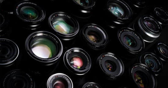 A close-up view of multiple camera lenses arranged closely together, showing their glass elements and reflections, with various brand markings visible on the lens rims.