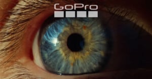 A close-up of a blue and amber human eye with a reflection visible in the pupil. The GoPro logo and four squares are positioned above the eye.