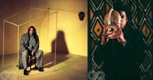 Left: A man in a gray suit sits on a chair inside a wireframe cube against a yellow background. Right: The same man holds a tribal mask in front of his face against a dark background with patterned masks on the wall.