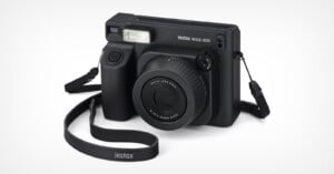 A black Fujifilm Instax Wide 400 instant camera with a textured grip, large lens, built-in flash, and attached black strap, displayed on a white background.