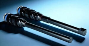 Two long, black camera lenses with extended barrels are shown on a blue background. One lens has a straight end, while the other has an angled tip, both featuring adjustment rings and metallic elements.