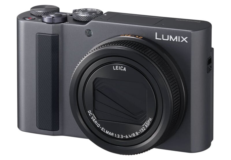 A compact Panasonic Lumix digital camera with a Leica lens is shown from a front angle against a white background. The lens is retracted and the camera is dark gray in color.