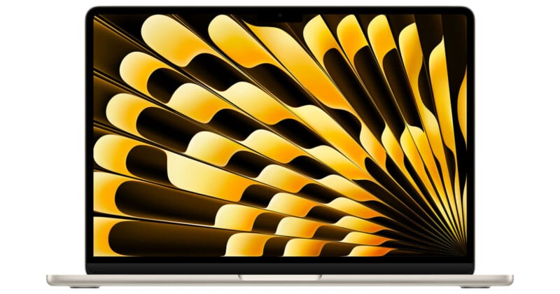 A silver laptop with its screen displaying an abstract pattern of yellow and black curved shapes radiating outward, creating a dynamic, sunburst-like effect. The laptop is open and viewed from the front.