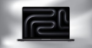 A laptop with a dark abstract pattern displayed on its screen, featuring curved and tubular shapes. The background is a soft gradient of gray and white tones.