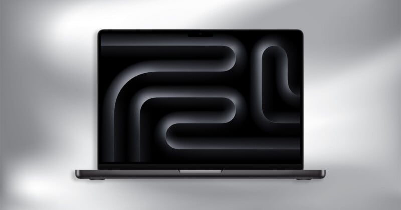 A laptop with a dark abstract pattern displayed on its screen, featuring curved and tubular shapes. The background is a soft gradient of gray and white tones.