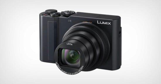 A black Panasonic Lumix digital camera with a Leica lens extended, shown against a plain white background. The camera has a textured grip on the left and the brand name "Lumix" visible on the upper right.