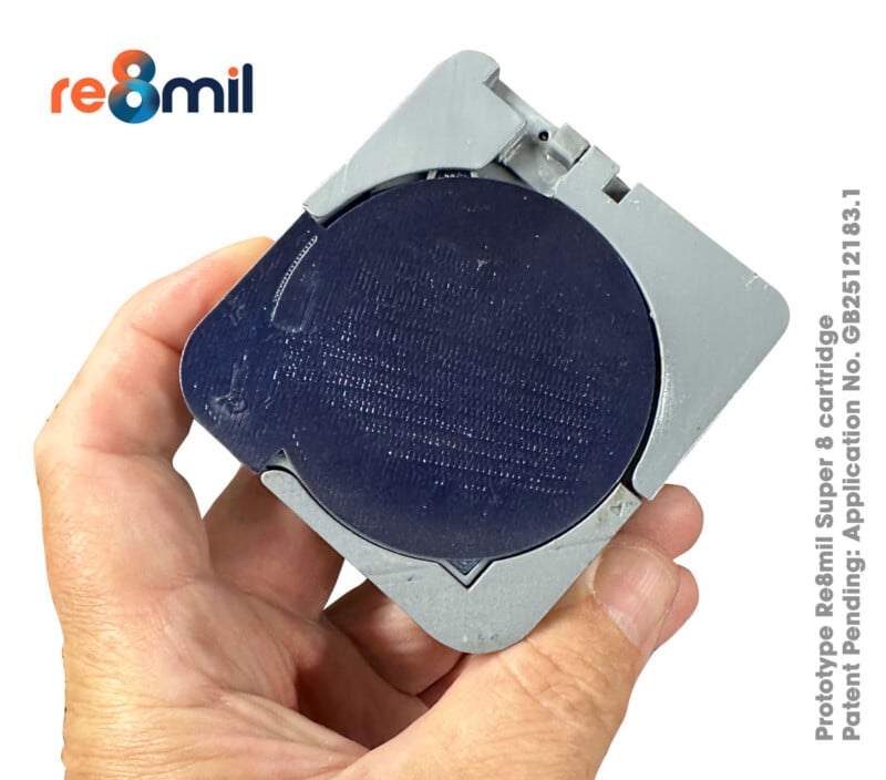 En una mano, sostiene un prototipo de cartucho de tinta Re8mil Super 8 cuadrado gris con una película redonda negra en su interior. El logotipo de Re8mil aparece en la esquina superior izquierda y la información de la patente está escrita a la derecha.