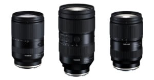 Three black Tamron camera lenses are displayed upright against a white background, showing different sizes and focal length markings on their barrels.