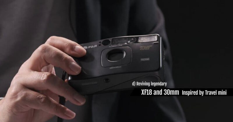 A hand holds a compact black Fujifilm camera. Text on the image reads: "d) Reviving legendary XF18 and 30mm Inspired by Travel mini." The background is dark and out of focus.