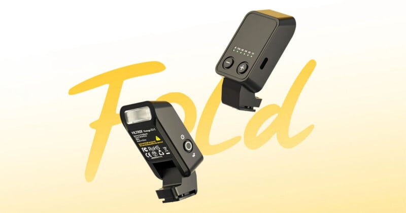 Two black camera flash units with buttons and indicator lights float against a yellow background with the word "Fold" in large, cursive text.