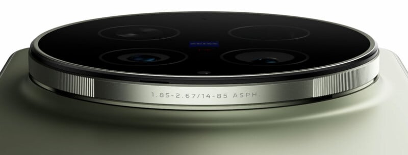 Close-up of a smartphone camera module with four lenses, Zeiss branding, and engraved lens specifications on a metallic ring, set against a smooth, matte surface.