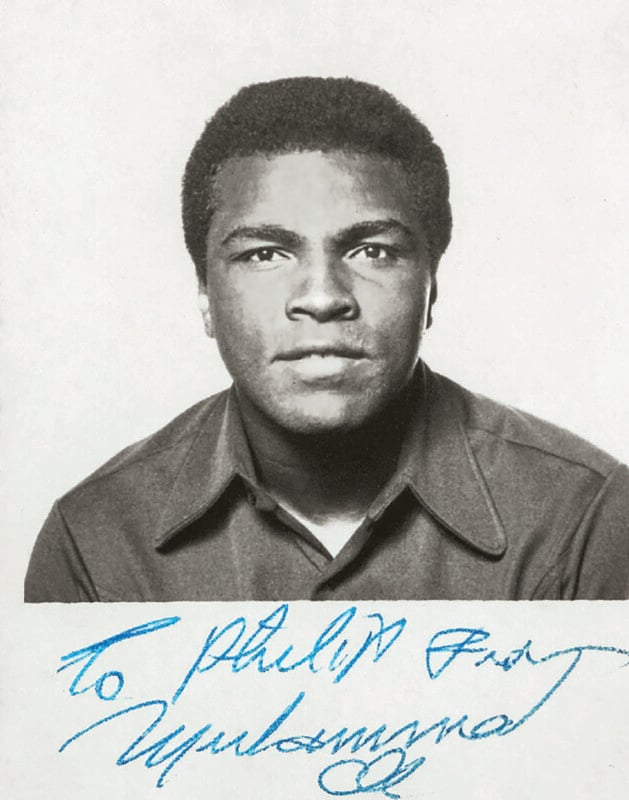 Black-and-white portrait of a young man facing forward, wearing a collared shirt. Below the image, there is a blue handwritten signature and a note that reads "To Philip Free.