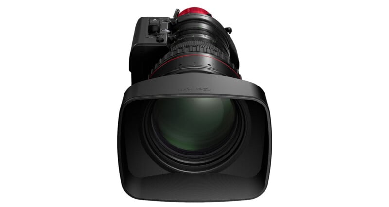 A professional video camera lens with a large rectangular lens hood, viewed from the front, showing detailed glass elements and the Canon logo on the hood.
