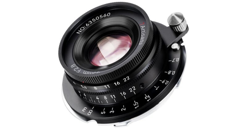Close-up of a 7Artisans 35mm f/2.8 camera lens with aperture and focus markings visible on the black metal body, showing its detailed mechanical construction.