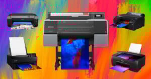 Five color photo printers, including models from Epson and Canon, are displayed against a vibrant rainbow-painted background, each printing a colorful, high-quality image.
