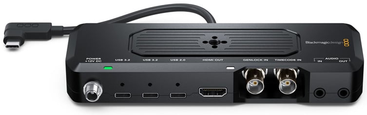 A Blackmagic Design video interface device showing multiple ports, including USB, HDMI out, Genlock, timecode in, audio in/out, and a power input, with a USB-C cable attached on the left side.