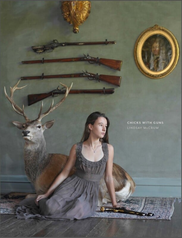 A young woman in a gray dress sits on the floor beside a taxidermy deer. Antique rifles hang on the wall behind her, along with a gold-framed portrait. The text reads, “CHICKS WITH GUNS LINDSAY MCCRUM.”.