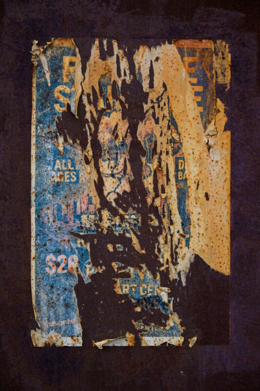 A tattered, weathered poster with blue and orange details is attached to a rusty brown surface. The poster shows torn sections revealing glimpses of text, including "ALL AGES," "$20," and "ART CEN.