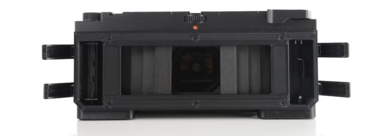 Rear view of an open vintage film camera with its back cover removed, revealing the film chamber, pressure plate, and internal mechanics.